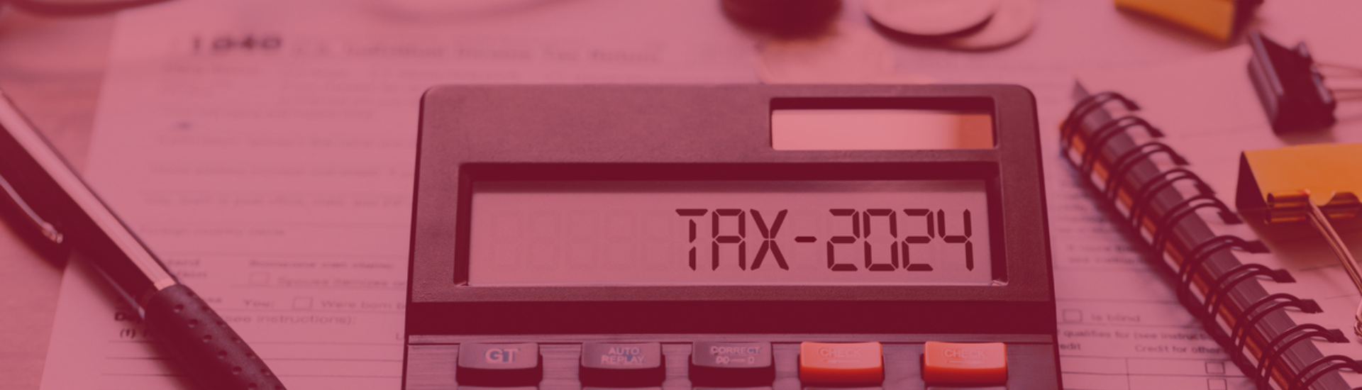 Calculator showing the words "Tax-2024" on the screen, surrounded by tax forms, notepads and coins.